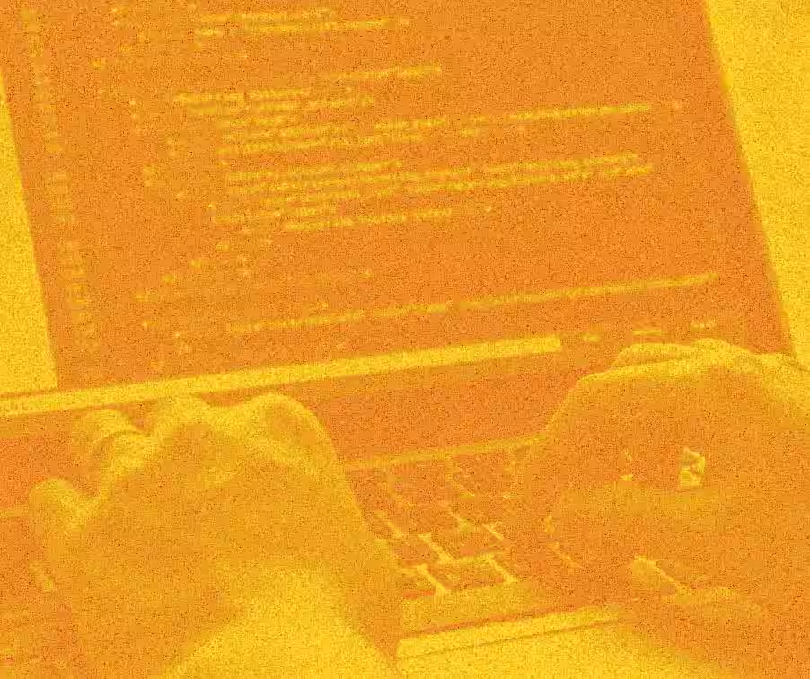 Orange duotone image of hands typing at a laptop with code onscreen.